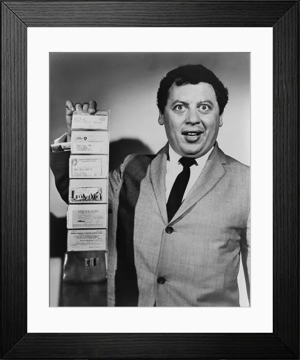 Framed Print : Comedian Marty Allen, holding wallet with four credit cards. Consumer credits cards, introduced in the 1950's, became common in the 1960's. 1960