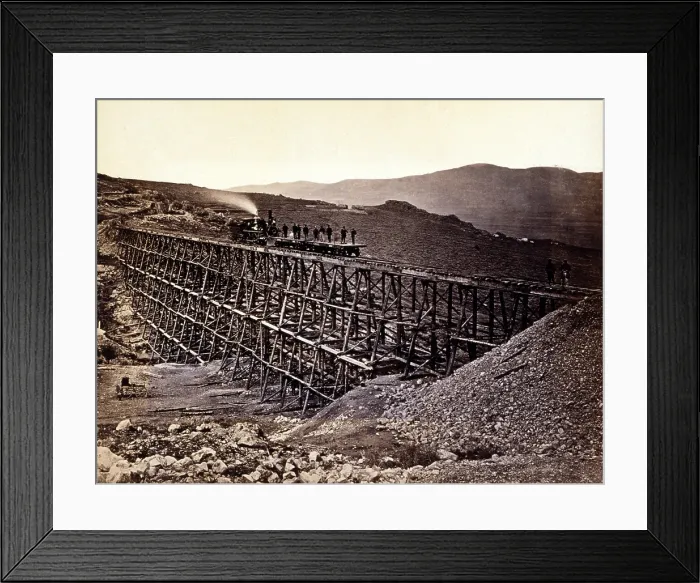 Framed Print : Trestle work. Central Pacific Railroad construction workers standing on railroad flatcars being pushed by locomotive across trestle at Promontory Point in Salt Lake Valley