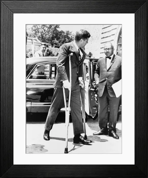 Framed Print : President John F. Kennedy on crutches accompanied by White House Press Secretary Andrew T. Hatcher on way to a conference in Washington, in June 1961 Framed Print : President John F. Kennedy on crutches accompanied by White House Press Secretary Andrew T. Hatcher on way to a conference in Washington, in June 1961