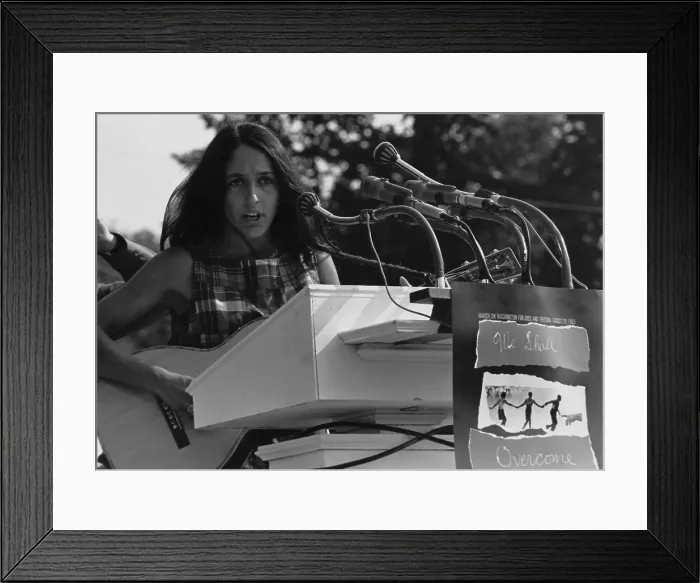 Framed Print : Folk Singer Joan Baez singing at the 1963 Civil Rights March on Washington. A sign hanging near the microphones reads We Shall Overcome. Aug. 28, 1963