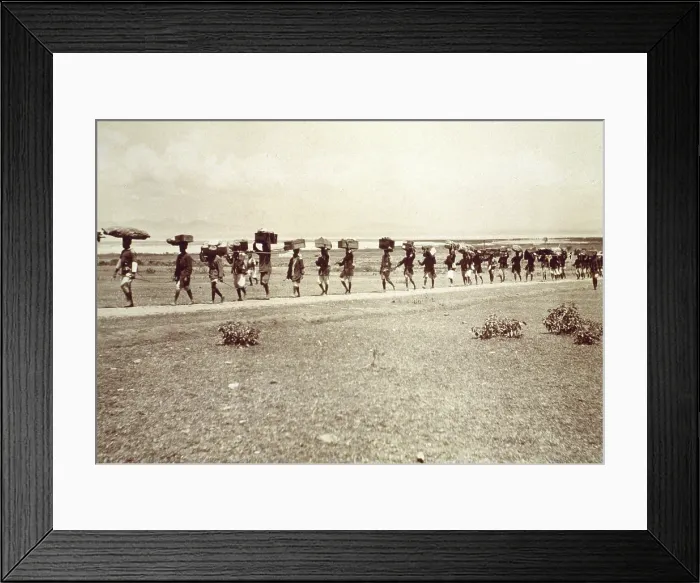 Framed Print : Theodore Roosevelt's 1910 African safari on the march, with a line of African men on road, carrying trunks, boxes and other items