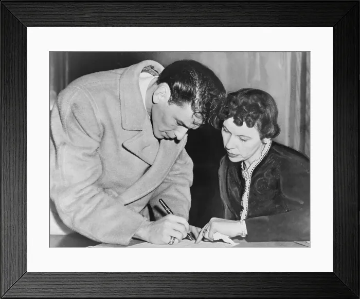 Framed Print : Frank Sinatra (1915-1998), signs his induction papers while Chief Clerk Mrs. Mae E. Jones helps out at local board No. 19-160 in Jersey City