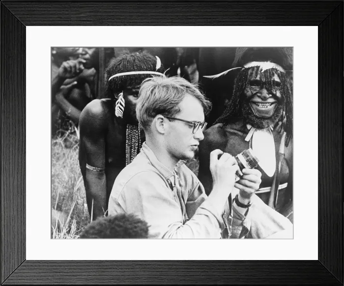 Framed Print : Michael C. Rockefeller (1934-1961) adjusting his camera in New Guinea, Papuan men in background. He disappeared while swimming to shore after a boating accident in New Guinea