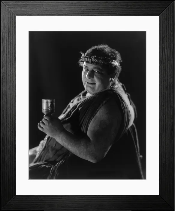 Framed Print : Actor from Mack Sennett comedy film in Roman toga seated holding wine glass. Ca. 1920