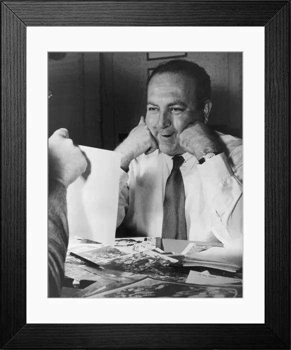 Framed Print : Film producer Val Lewton smiling as he looks at a photograph, in the 1940s. Photo from his personal papers. (BSLOC_2015_14_174)