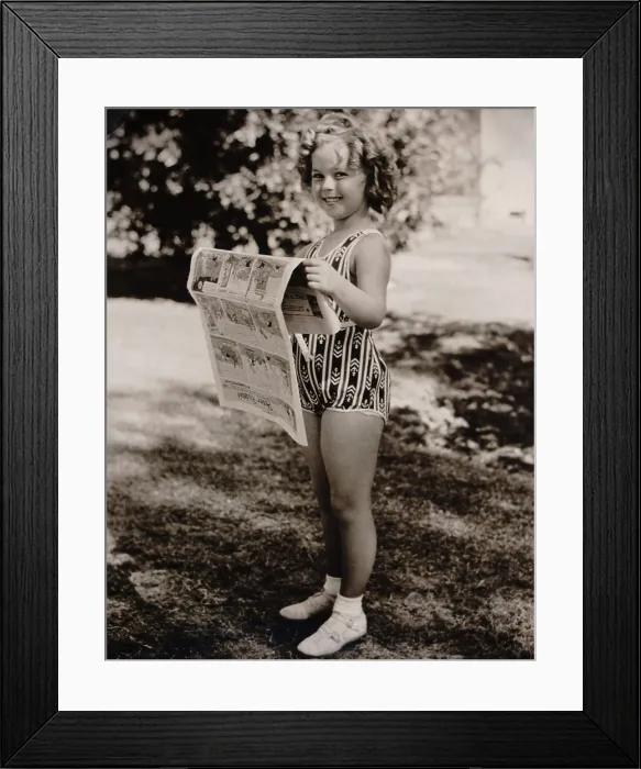 Framed Print : Child actress, Shirley Temple, reads the funny papers at the Desert Inn, Palm Springs, March 6, 1936 (BSLOC_2018_3_12)