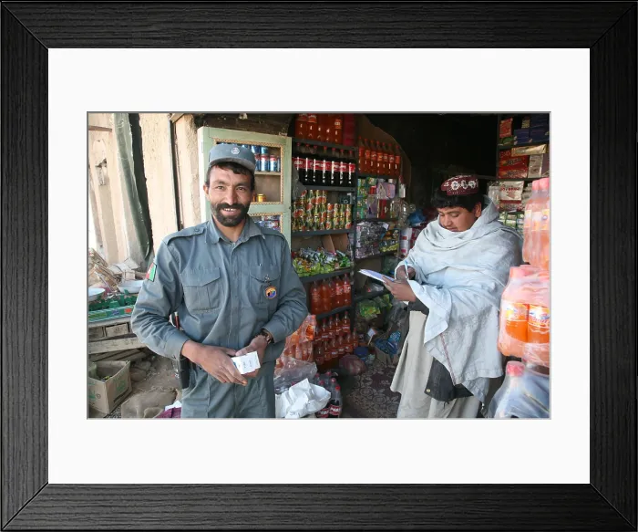 Framed Print : Afghan National Police officer shops at a store in Now Zad Helmand province Afghanistan. Residents have returned after the expulsion of the Taliban by U.S. Marines. Feb