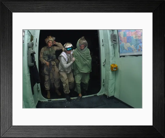 Framed Print : U.S. Sailor and a Marine bring a wounded Pashtun fighter from Afghanistan aboard the USS Bataan for medical treatment in the first months of the U.S
