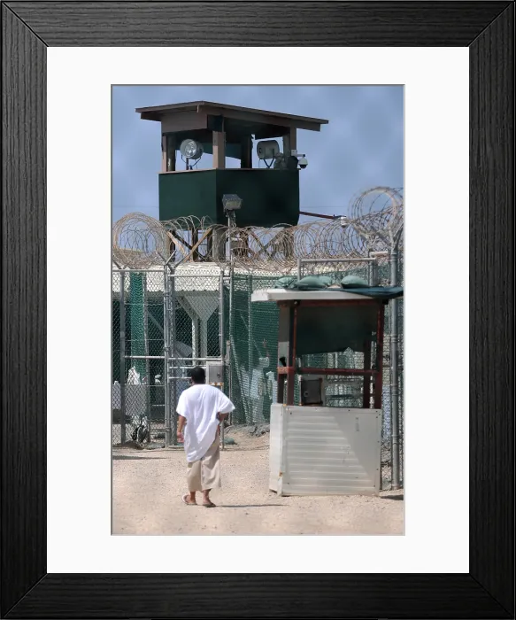 Framed Print : Under the guard tower a detainee walks in the recreation yard at Camp Delta the military prison for suspected Taliban and Al-Qaeda combatants at Guantanamo Bay Naval Base Cuba