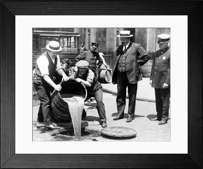 Framed Print : New York City Deputy Police Commissioner John A. Leach, right, watching agents pour liquor down a manhole following a raid during prohibition 1921