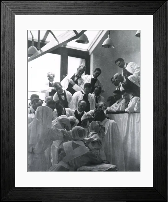 Framed Print : Charles H. Mayo (1865-1939), at center right in surgical gown, cap, and mask, in an operating amphitheatre assisted by four nurses and observed by others in the gallery
