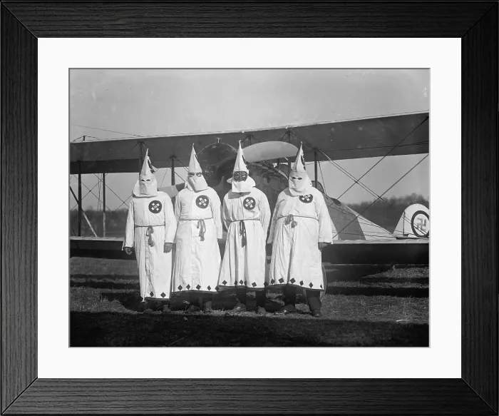 Framed Print : Four hooded Ku Klux Klan members pose in from of their airplane which bears a swastika emblem. 1922 photo