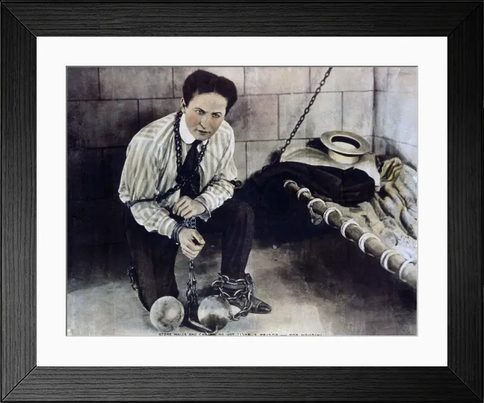 Framed Print : Harry Houdini (1874-1926), in still from a movie he made with Famous Players-Lasky Corporation, shows him chained in a prison cell, from which he will escape. Ca. 1915