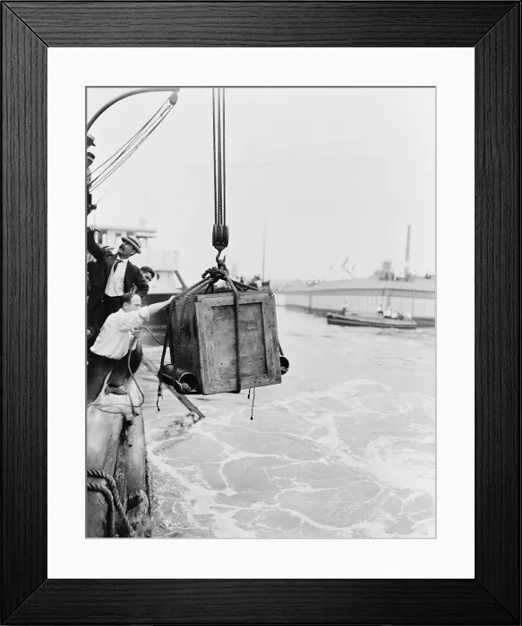 Framed Print : Harry Houdini (1874-1926) in the crate being lowered from ship into water in New York harbor, ca. 1914