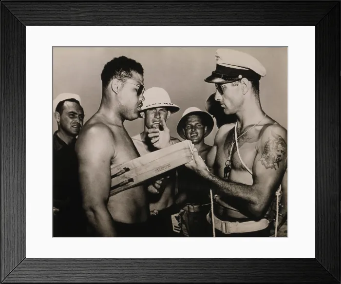 Framed Print : Staff Sergeant Joe Louis, world champion heavyweight, is instructed in the use of a lifebelt while touring bases during World War II