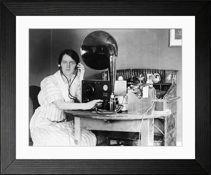 Framed Print : Woman listening to radio in her home receiving a personal radio message telling her when her husband will arrive home. 1922