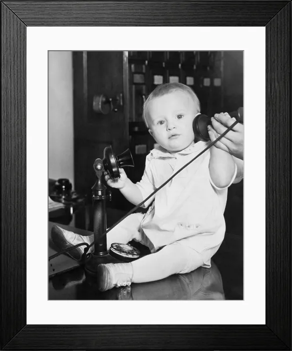 Framed Print : A baby found under a bed at the Stevens Hotel, Chicago, Illinois was photographed with a telephone to illustrate the many phone calls from people wanting to give him a home. 1930