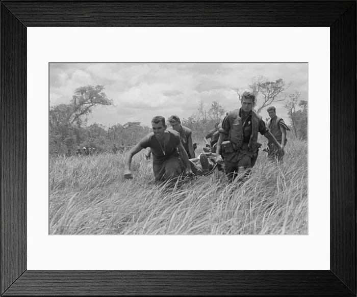 Framed Print : Vietnam War. While under heavy fire, US Marines are carry a wounded Marine to the evacuation helicopter near the Demilitarized Zone (DMZ) dividing North and South Vietnam
