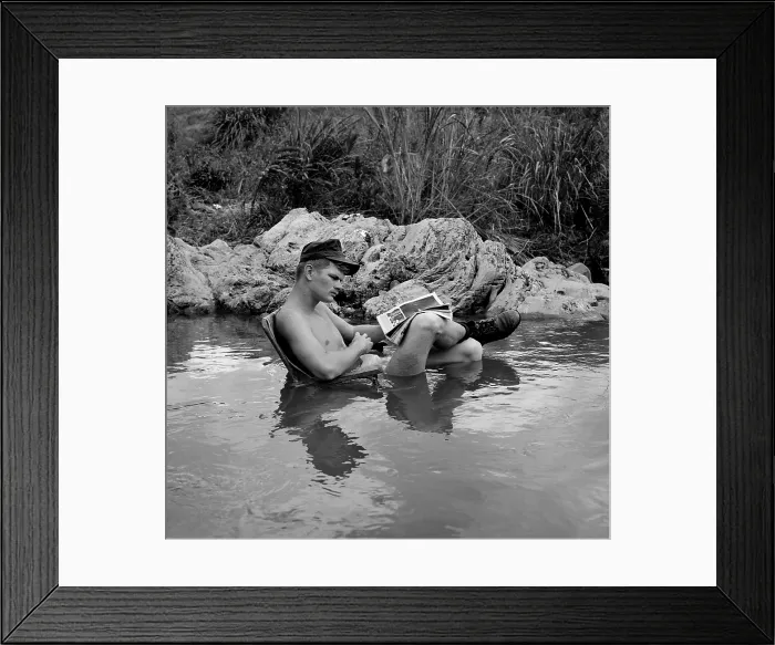 Framed Print : Vietnam War. US Marine rifleman takes time out to relax in a cool mountain stream, with an easy chair and his favorite magazine. 1968