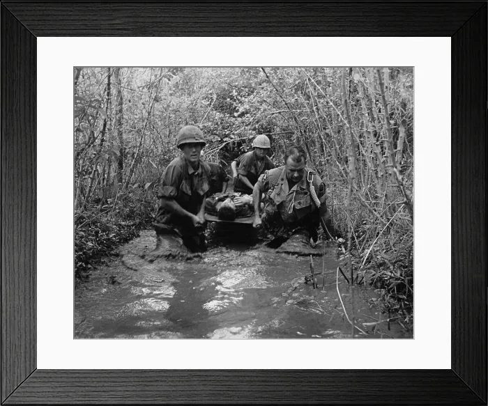 Framed Print : Vietnam War. US Soldiers carry a wounded comrade through a swampy area. 1969