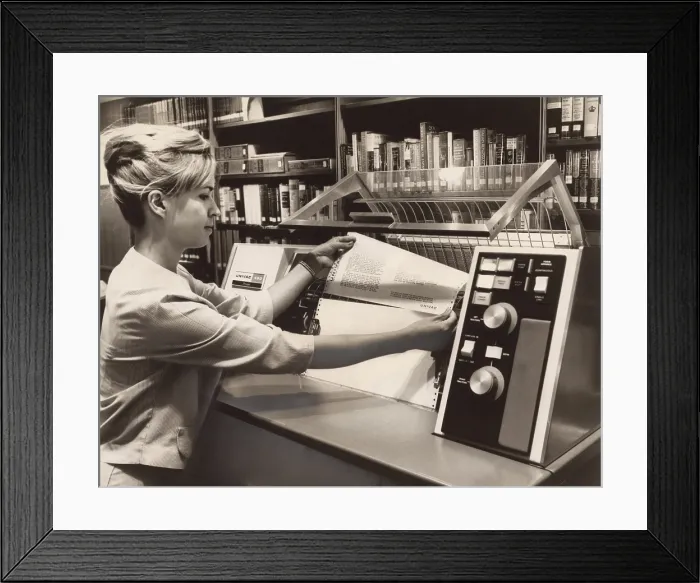 Framed Print : Librarian taking a printout from a UNIVAC 490 Printer. In the 1960s computer technology was available for specialists in this case to manage library catalogs and book circulation
