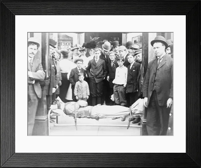 Framed Print : Harry Houdini (1874-1926), strapped to cot, with onlookers crowded around him in front of Keith's Theater, Boston, a major venue on the Vaudeville Circuit. Ca. 1910 Framed Print : Harry Houdini (1874-1926), strapped to cot, with onlookers crowded around him in front of Keith's Theater, Boston, a major venue on the Vaudeville Circuit. Ca. 1910
