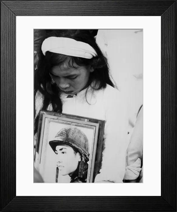Framed Print : An young Vietnamese widow mourns. Hugging a photo of her missing husband, she attends a mass funeral service for 400 killed in Hue during the Tet Offensive. Oct. 14, 1968
