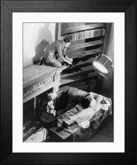 Framed Print : Cecil Beaton (1904-1980), kneeling on mantle of fireplace to take photograph of Lilyan Tashman (1899-1934), movie actress, reclining on chaise in Hollywood, California. Ca. 1930