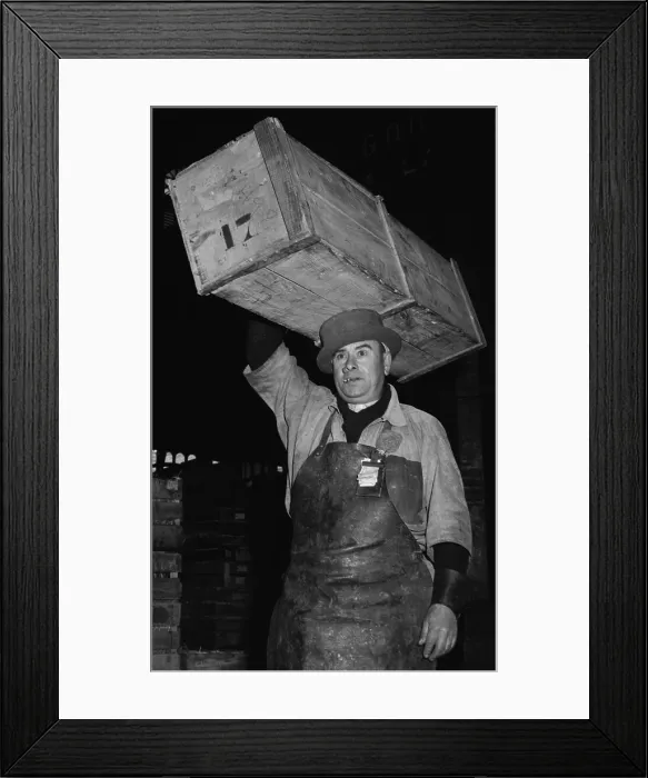 Framed Print : Porter at Paris Central Market wearing a special, narrow-brimmed, hard-crowned hat to help balance the crate of fish he is carrying on his head. 1946
