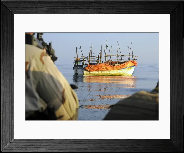 Framed Print : Back view of U.S. sailors with weapons ready as they approach a ramshackle dhow in the Gulf of Aden. Such boats are used by pirates and refugees. Jan