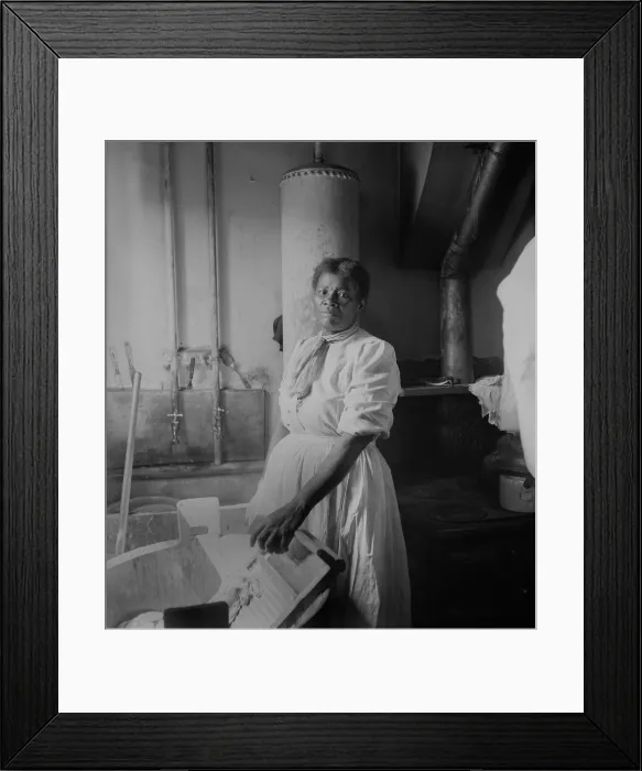 Framed Print : African American woman standing by a washtub with her hand on a washboard. Ca. 1920