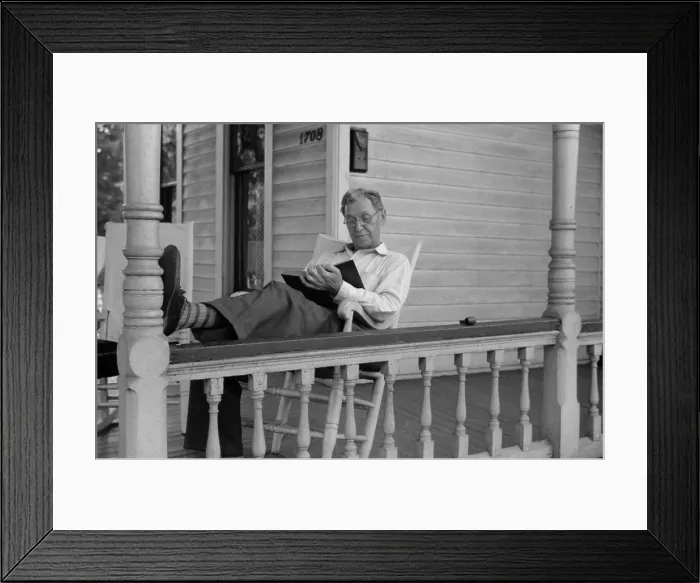 Framed Print : Reading a good book. Middle age man reading on his front porch on a Sunday afternoon in July 1941. Vincennes, Indiana