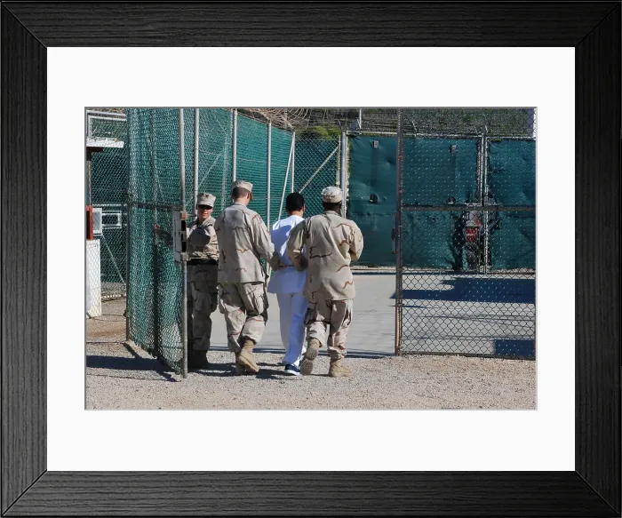 Framed Print : U.S. Navy guards escort a detainee through Camp Delta the military prison for enemy combatants many believed to be associated with Al-Qaeda or the Taliban Framed Print : U.S. Navy guards escort a detainee through Camp Delta the military prison for enemy combatants many believed to be associated with Al-Qaeda or the Taliban