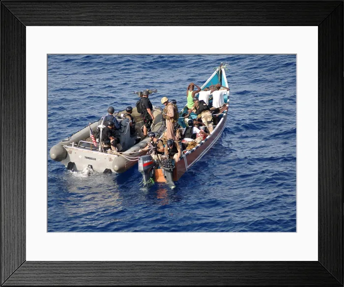 Framed Print : U.S. Navy sailor inspects the outboard engines on a skiff suspected of participating in recent pirate activity while fellow sailors board search and question men on ship