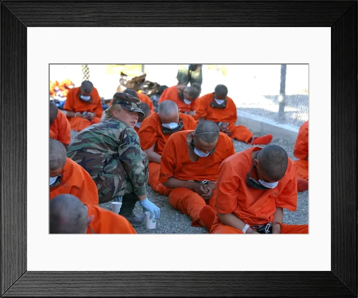 Framed Print : U.S. Military Police woman provides water to chained detainees as they arrive at Camp X-Ray at Guantanamo Bay Naval Base. The prisoners were believed by the U.S Framed Print : U.S. Military Police woman provides water to chained detainees as they arrive at Camp X-Ray at Guantanamo Bay Naval Base. The prisoners were believed by the U.S
