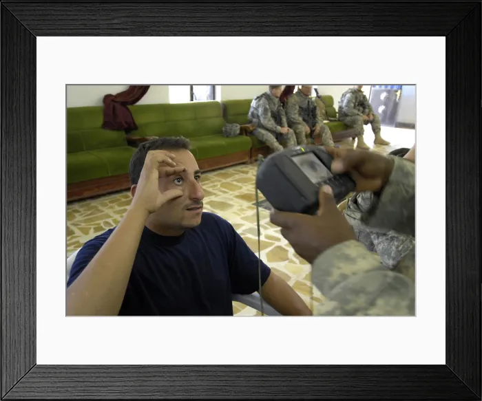 Framed Print : An Iraqi candidate for the Sons of Iraq security force holds his eye open for a retinal scan administered by a US Soldier in Wasit Province Iraq. April 1 2008. (BSLOC_2011_12_287)