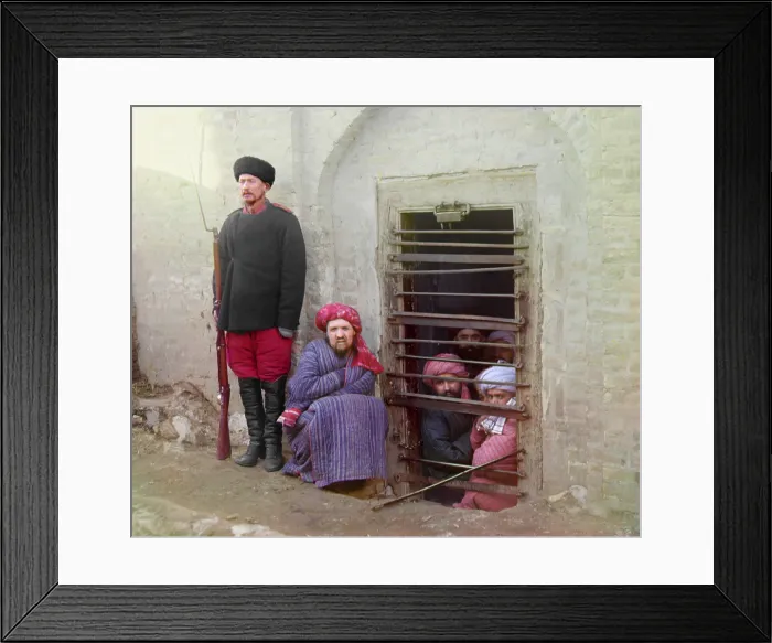Framed Print : Traditional Central Asian prison, with cells cut into the ground. Turbaned Inmates looking out through the bars while guard stands by with a Russian rifle, uniform, and boots Framed Print : Traditional Central Asian prison, with cells cut into the ground. Turbaned Inmates looking out through the bars while guard stands by with a Russian rifle, uniform, and boots