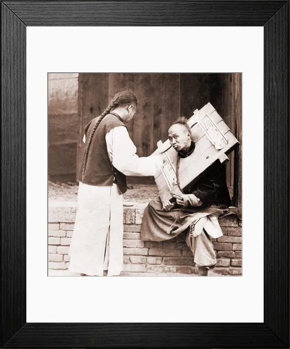 Framed Print : Charitable Chinese man feeding a criminal in a cangue. Petty criminals were sentenced to wear the canque, often for a couple of months, and display themselves in public places