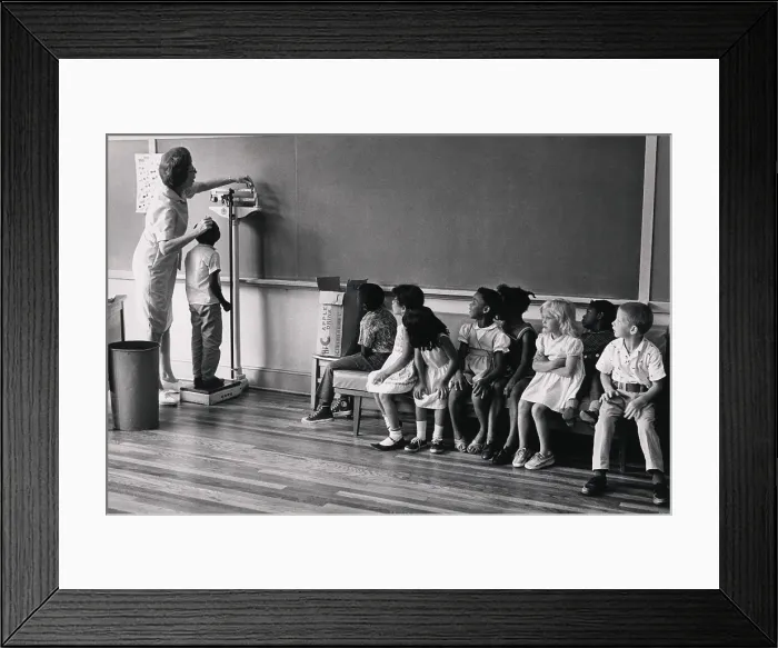 Framed Print : Children of migrant workers being measured for height, at school for children in New Jersey, 1956. Photograph by Louise Rosskam