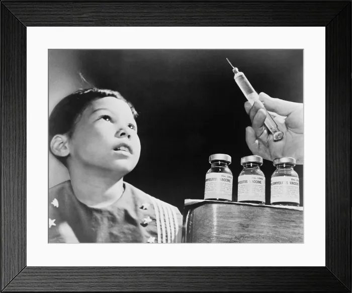 Framed Print : Child looks at a syringe with poliomyelitis vaccine. The Salk Vaccine, developed in 1955, was distributed worldwide and to prevent Polio