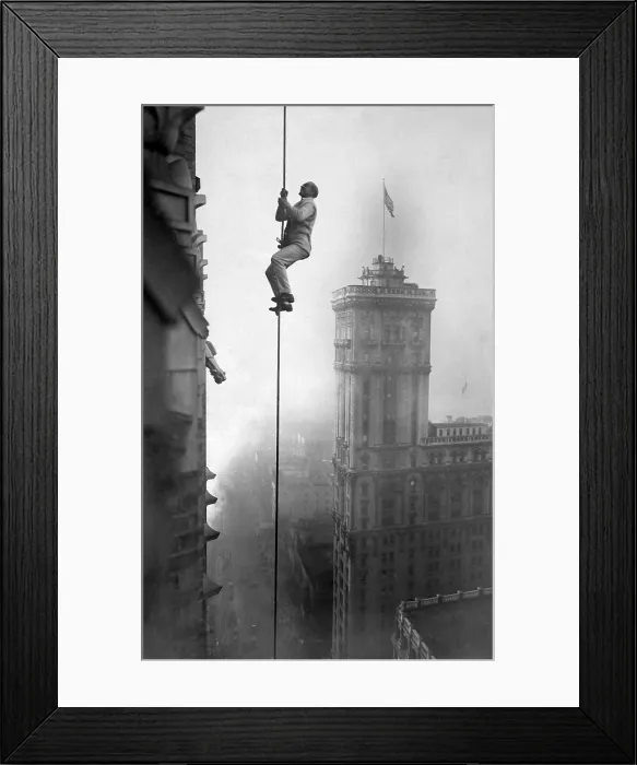 Framed Print : A man, identified as the human squirrel, climbing at a dizzy height above Times Square to promote War Relief Fund contributions. World War I. Ca. 1918 Framed Print : A man, identified as the human squirrel, climbing at a dizzy height above Times Square to promote War Relief Fund contributions. World War I. Ca. 1918