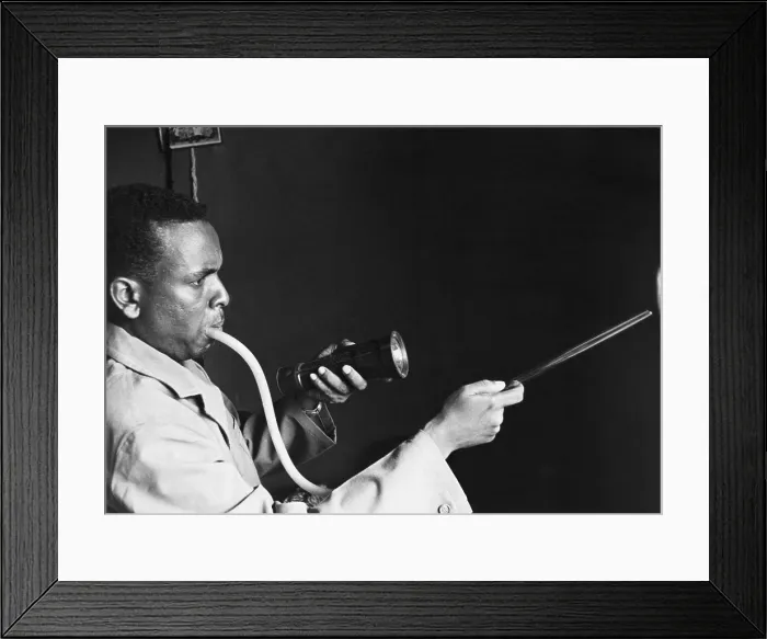 Framed Print : Togolese man using a mouth inhaler to capture mosquitoes to prevent the spread of malaria. 1964