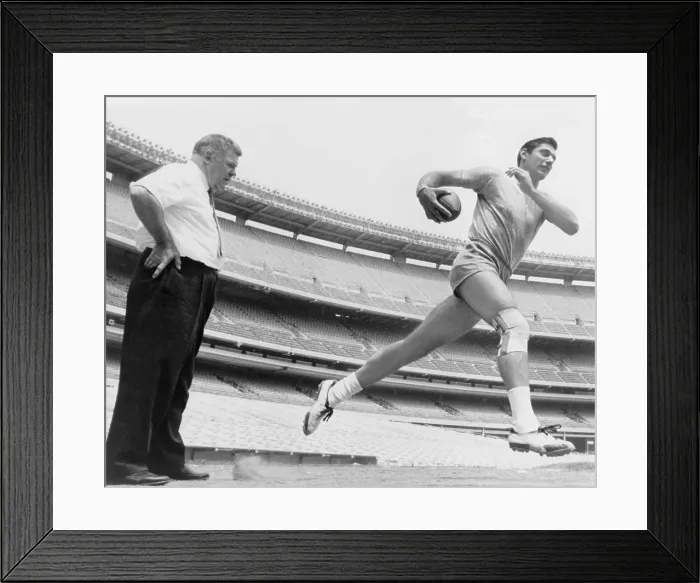 Framed Print : Joe Namath (b. 1943), quarterback with the New York Jets, running during light workout to test his injured knee, as coach Weeb Eubank observes