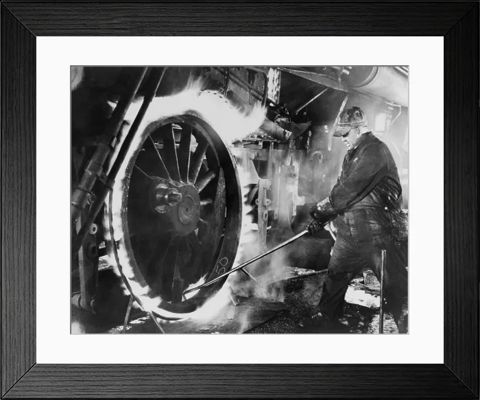Framed Print : Railroad worker sweating a tire on a locomotive wheel. This is the process of heating the circular metal tire, expand it to fit around a metal wheel