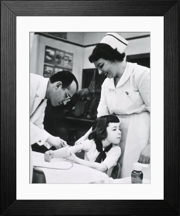 Framed Print : Jonas E. Salk (1914-1995), American physician who developed the first effective Polio vaccine inoculating child as nurse stands by. Ca. 1955