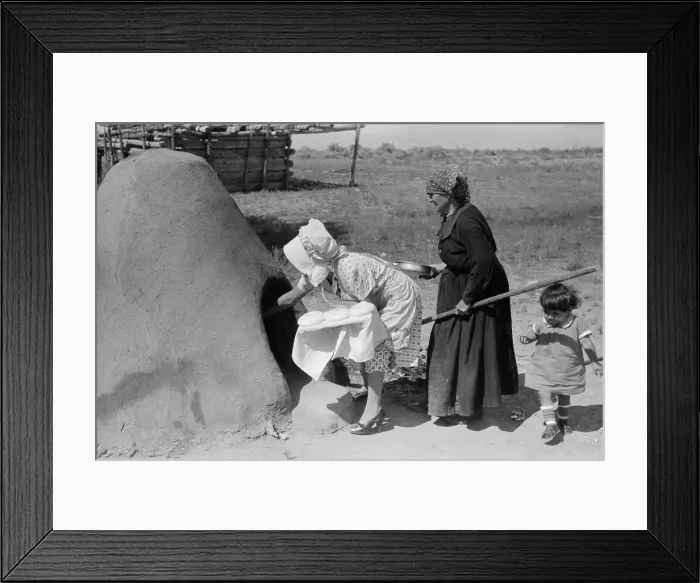 Framed Print : Two Spanish-American women placing loaves of bread in outdoor earthen oven for baking, Taos County, New Mexico