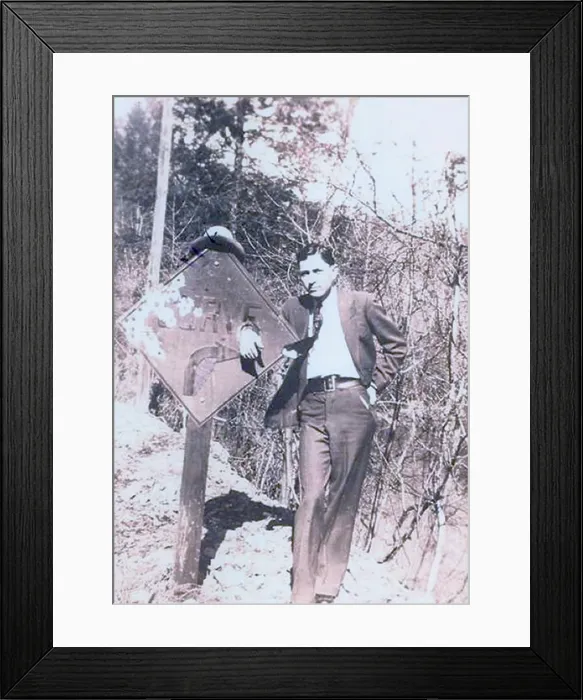 Framed Print : Clyde Barrow (1909-1934) dressed in a suit and standing with his hand place through a hold on a road sign Framed Print : Clyde Barrow (1909-1934) dressed in a suit and standing with his hand place through a hold on a road sign
