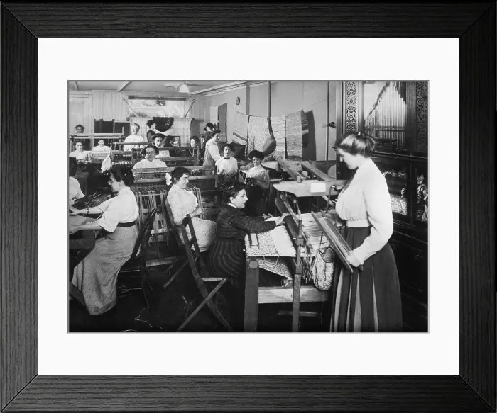 Framed Print : Blind women weaving at looms accompanied by an orchestrion, a self playing musical instrument, at right. Photo taken by Byron Company for the New York Association for the Blind