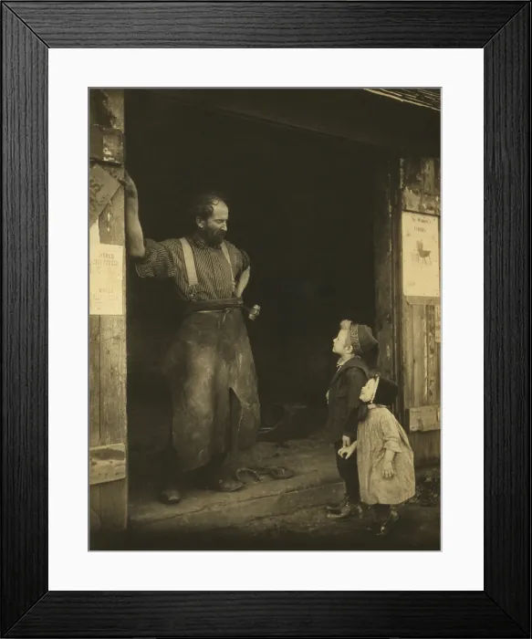 Framed Print : An leather aproned blacksmith in the doorway of his forge talking to two youngsters. Photograph by Frances Stebbins Allen, c. 1900