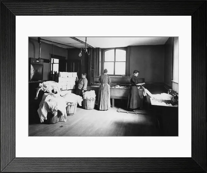 Framed Print : Laundry with women working at large sinks, one operating a hand cranked wringer, and another at a drying rack placed near a stove. Boston, Massachusetts, 1905
